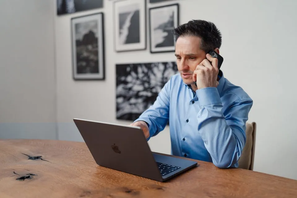 Alex Pippir telefoniert lächelnd am Laptop