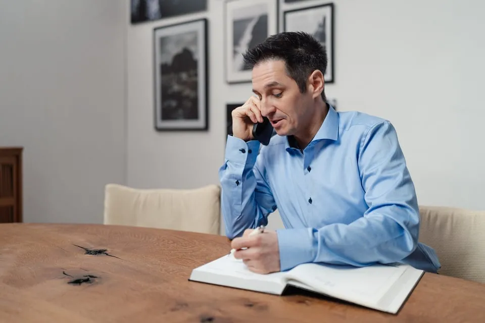 Alex Pippir telefoniert und schreibt Notizen in ein Buch